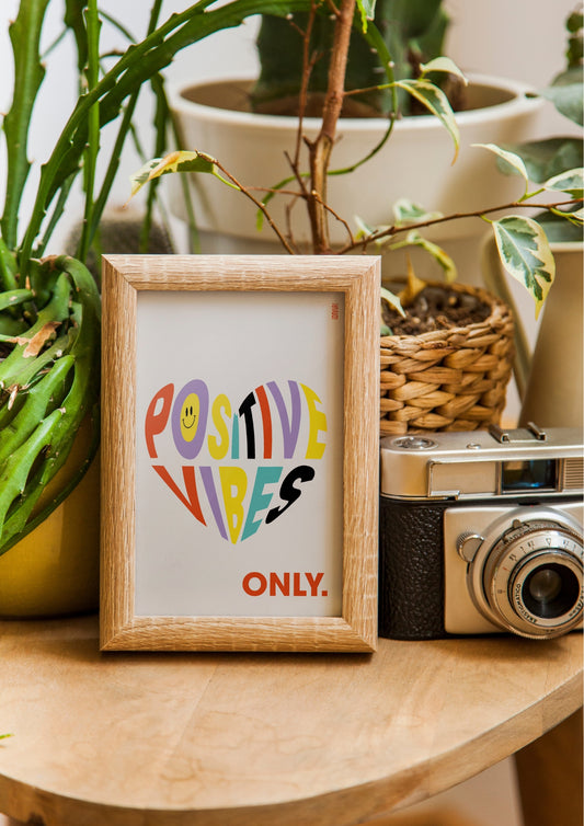 Affiche avec fond blanc cassé. Au centre un coeur avec le texte "Positive Vibes Only". Les lettre sont de toutes les couleurs.