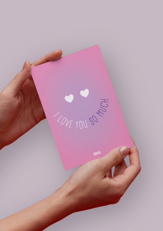 Carte avec un dégradé de rose avec un smiley au centre. Les yeux du smiley sont en forme de coeur, et la bouche est représentée par le texte "I love you so much".
