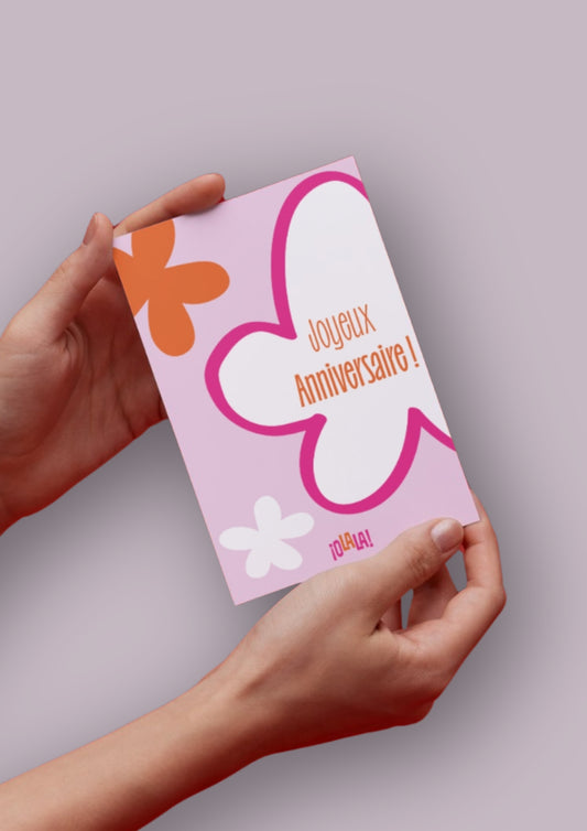Carte Joyeux anniversaire avec pour design un fond rose, 3 fleurs rose, blanche et orange et le logo OLALA en bas.