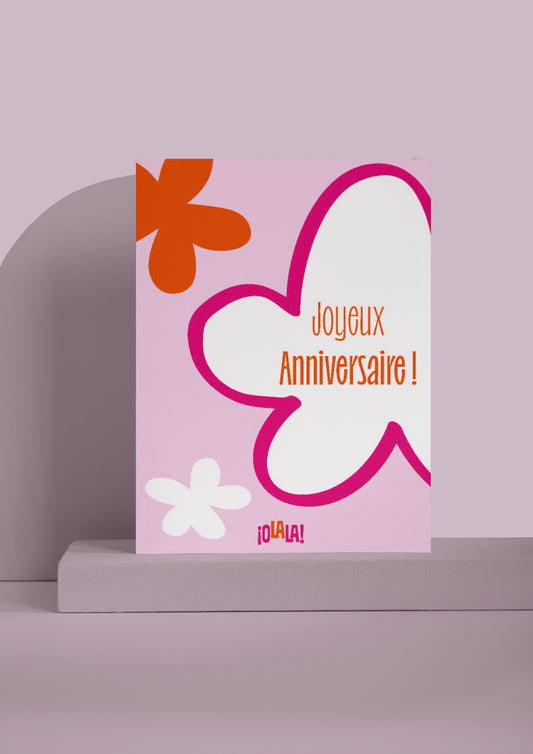 Carte Joyeux anniversaire avec pour design un fond rose, 3 fleurs rose, blanche et orange et le logo OLALA en bas.