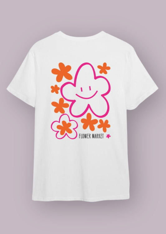 Photo produit d'un t-shirt blanc avec un design qui représente des fleurs rose et orange. La plus grande a un smiley dedans et les mots flower market sont en bas à droite du design. 